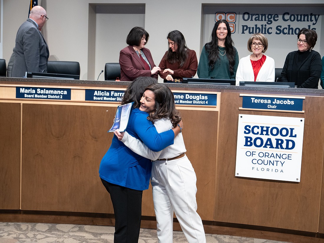 Anne Douglas and Gloria Boisvert hug at the School Board meeting where the recognition took place.