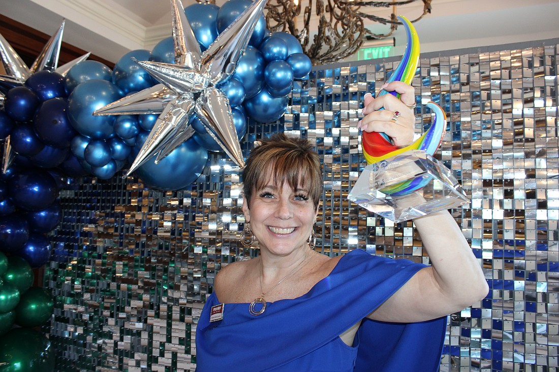 Shawna Hicks-Cranston of PostNet raises her Sandies award for the Community Champion category. The annual Sandies was held by the Lakewood Ranch Business Alliance Nov. 14 at the Grove in Lakewood Ranch.
