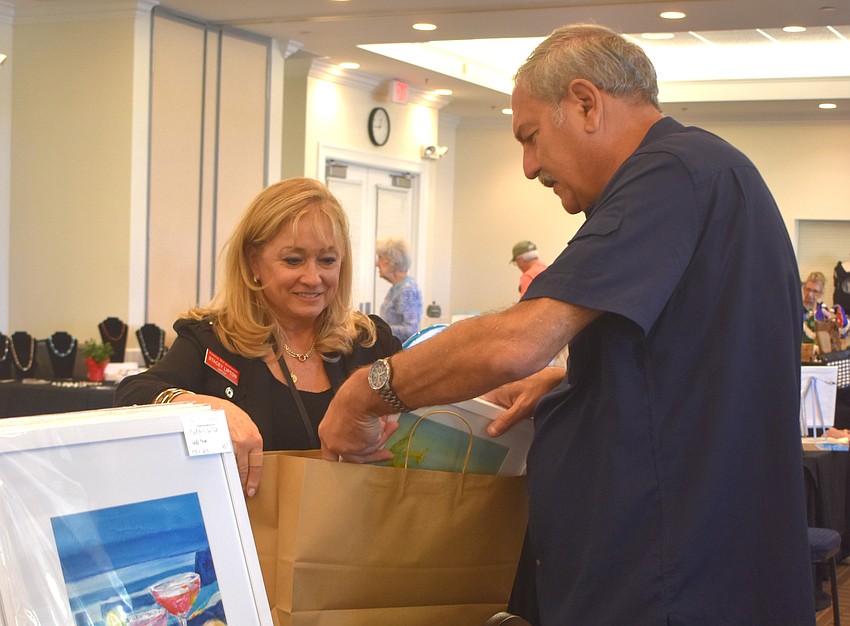 Stacey Lipton helps to bag up a hummingbird themed art piece purchased by Lakewood Ranch's Raymond Rahi. Rahi said she is incredible and he loves birds and the colors used.