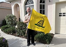 John Morrison takes his Gadsden flag down after receiving two notices from his homeowners association saying the flag violates community deed restrictions.