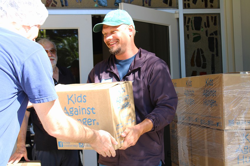 Volunteer Charles Dempsey passes along a box packed with meals to support families in need as part of a recent event at St. Armands Key Lutheran Church.