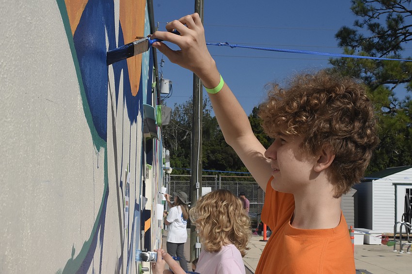 Juniper Coleman, 11, and her brother Calvin Coleman, 13, paint the mural.