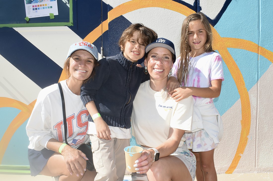 Sheena Works, Sebastian Works, 7, Alissa Silvers, and Isabella Coulton, 7, pose together in front of the mural.