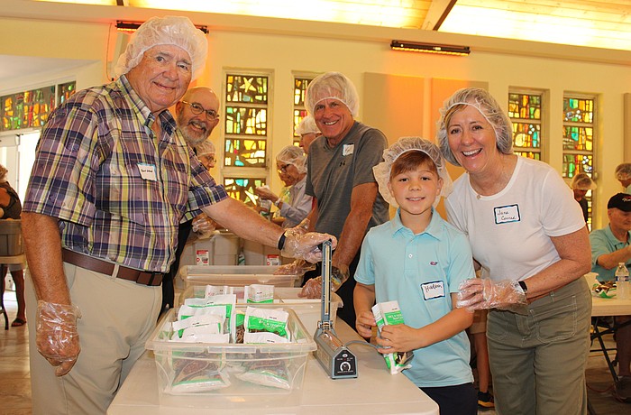 Bert Wood, Karl Kaminski, Hudson Nesmith and Jane Conrad were among the 120 volunteers helping pack meals for Kids Against Hunger on Nov. 8 at St. Armands Key Lutheran Church. Part of the meals went to help local families, and part went to support hurricane survivors in Jamaica.
