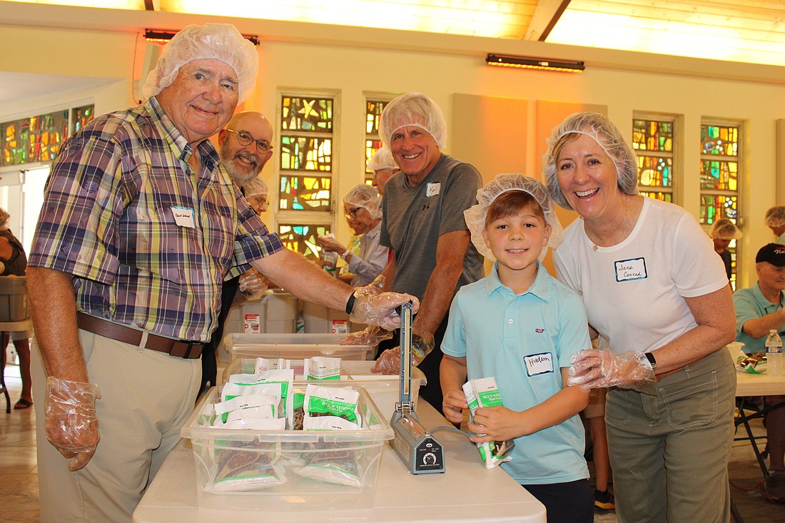 Bert Wood, Karl Kaminski, Hudson Nesmith and Jane Conrad were among the 120 volunteers helping pack meals for Kids Against Hunger on Nov. 8 at St. Armands Key Lutheran Church. Part of the meals went to help local families, and part went to support hurricane survivors in Jamaica.