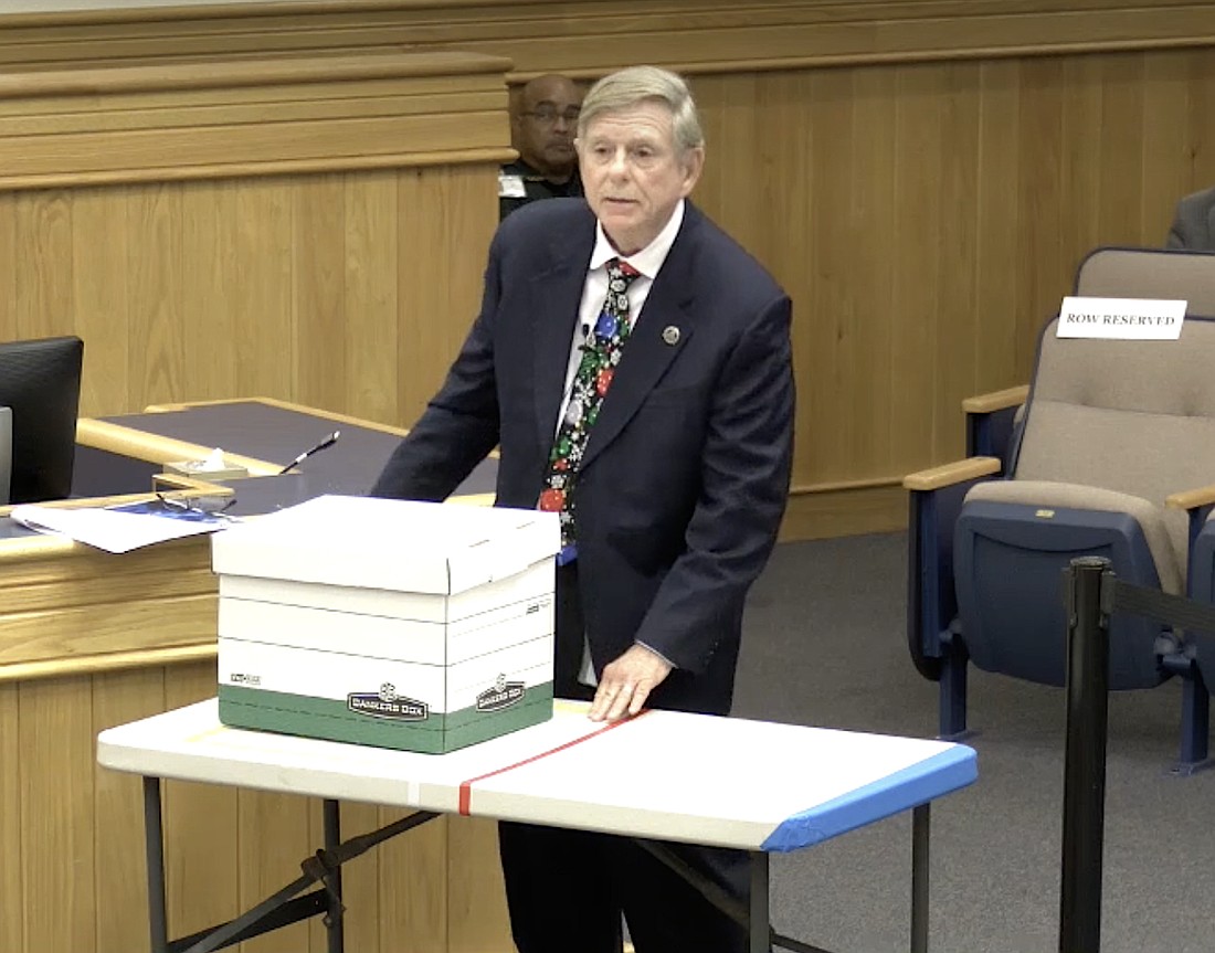 Sarasota County Commissioner Mark Smith uses a table to illustrate a beachfront lot and a box to illustrate building size and height to argue for a Comprehensive Plan change for voluntary redevelopment.