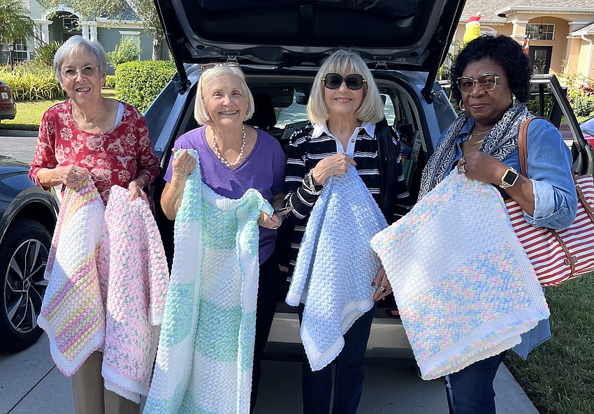 Mission in Motion's Judy Kirkpatrick, Debbie Apple, Rose Marie Hartley and Ruth Barker handle 60 blankets handmade by one of their members to be donated to new mothers and babies.