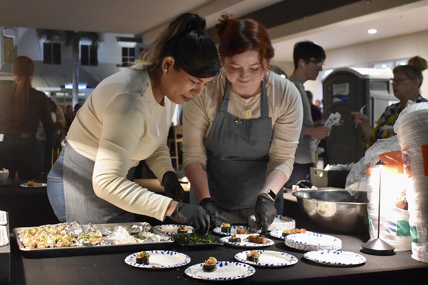 Summer Walker and Sara Sandoval plate up samples of spring rolls, sushi and pork belly.
