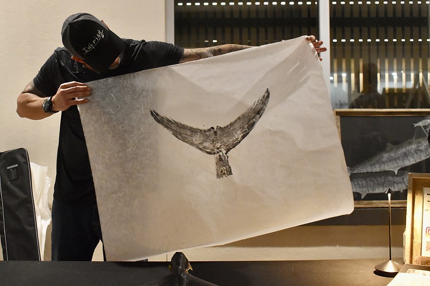 Joseph Koukl pulls the rice paper off the tuna tail to reveal the print.