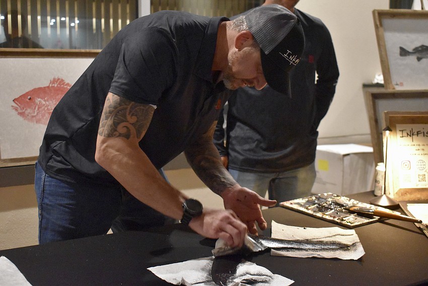 Joseph Koul, owner of Inkfish, paints the tuna's tail to make an art print.