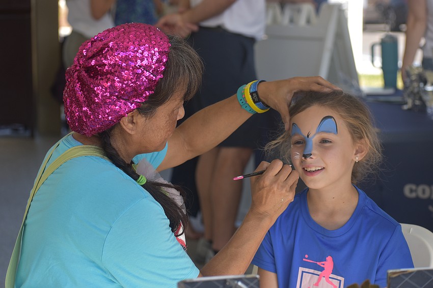 Akiko Campbell of Akiko Graphics paints a blue cat on the face of 8-year-old Summerfield resident Phoebe Newman.