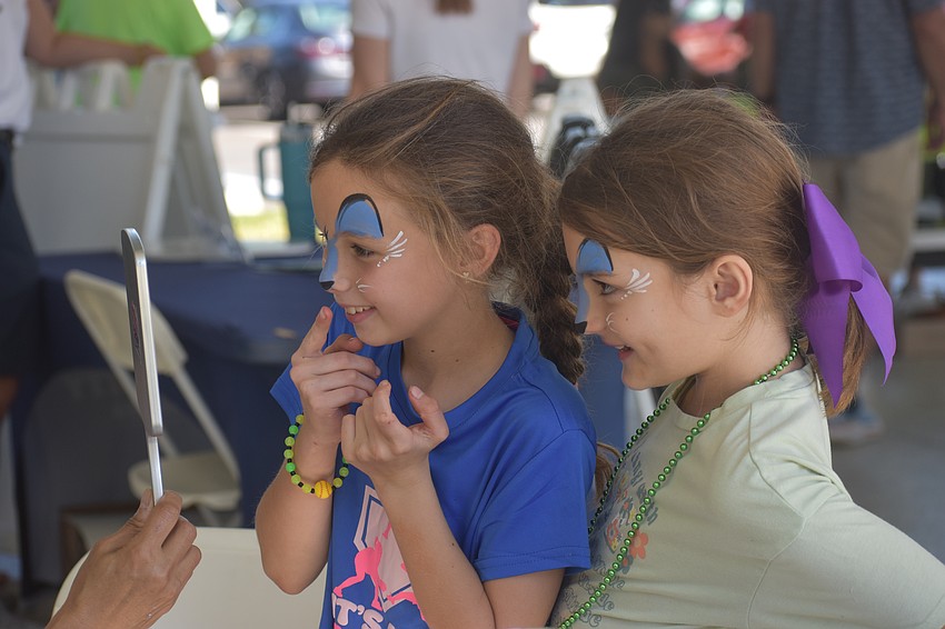 Summerfield resident Phoebe Newman, 8 and Polo Run resident Penelope Gouvna, 7, check out their blue cat faces painted by Akiko Graphics.