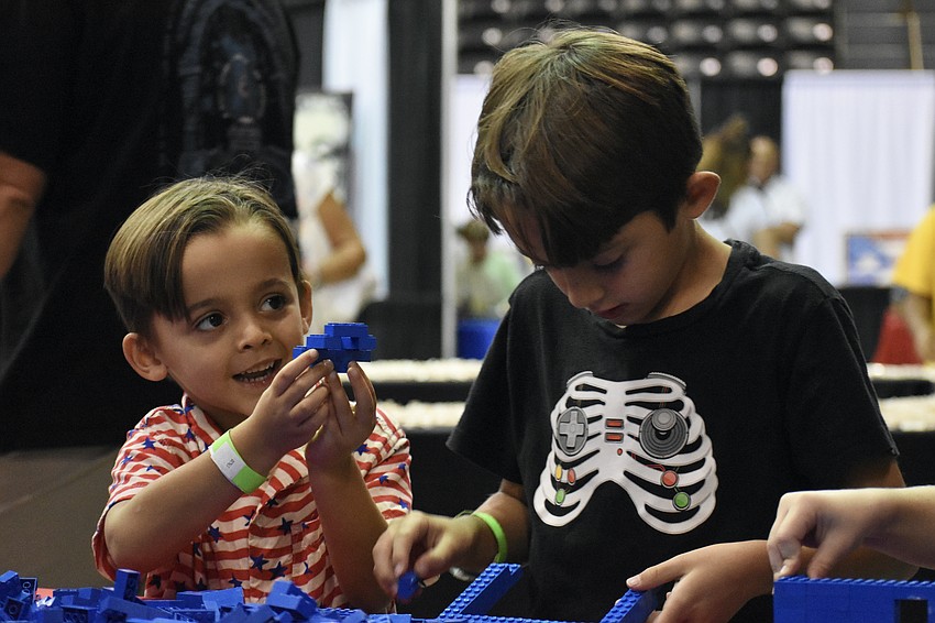 Hudson Barnett, 4, shows his work to his grandmother Elizabeth Henson, while his brother Nolan Barnett builds a Lego creation alongside him.