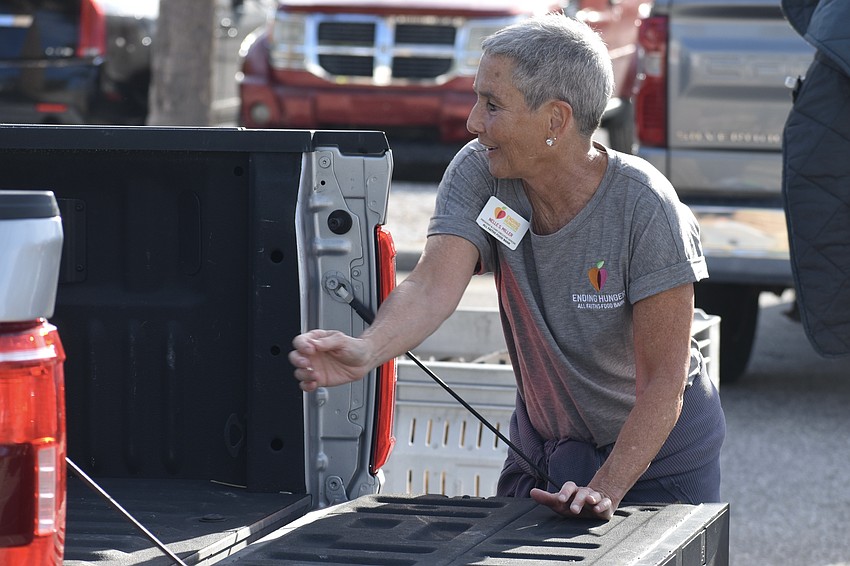 Nelle Miller, president and chief executive officer of All Faiths Food Bank, helps load an attendee's truck.