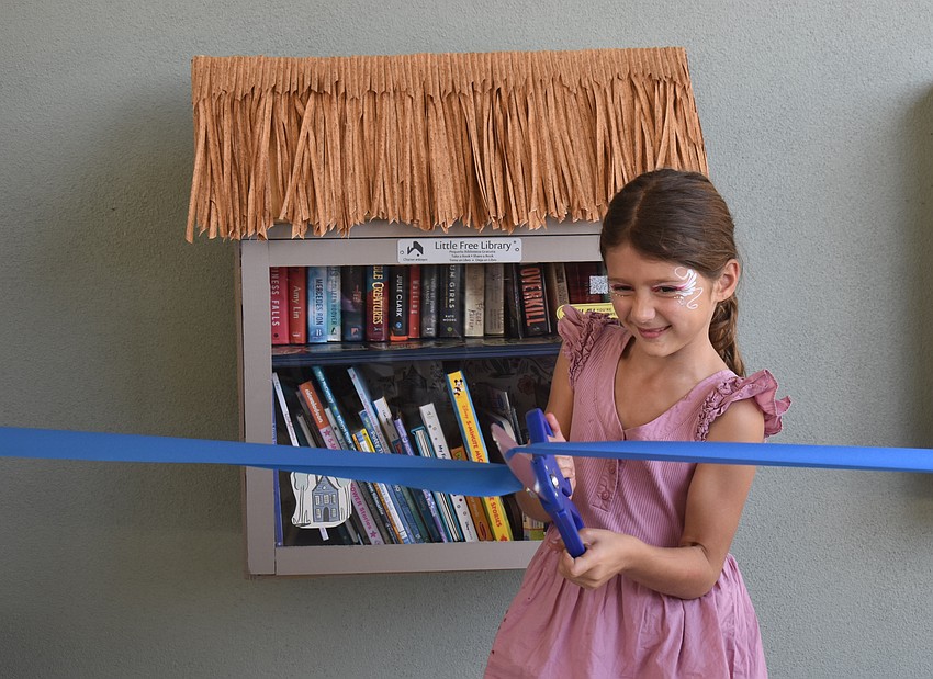 Millie Monserez, 7, was proud to cut the ribbon for the Little Free Library, but was also scared she would cut her finger straight off with the oversized scissors.
