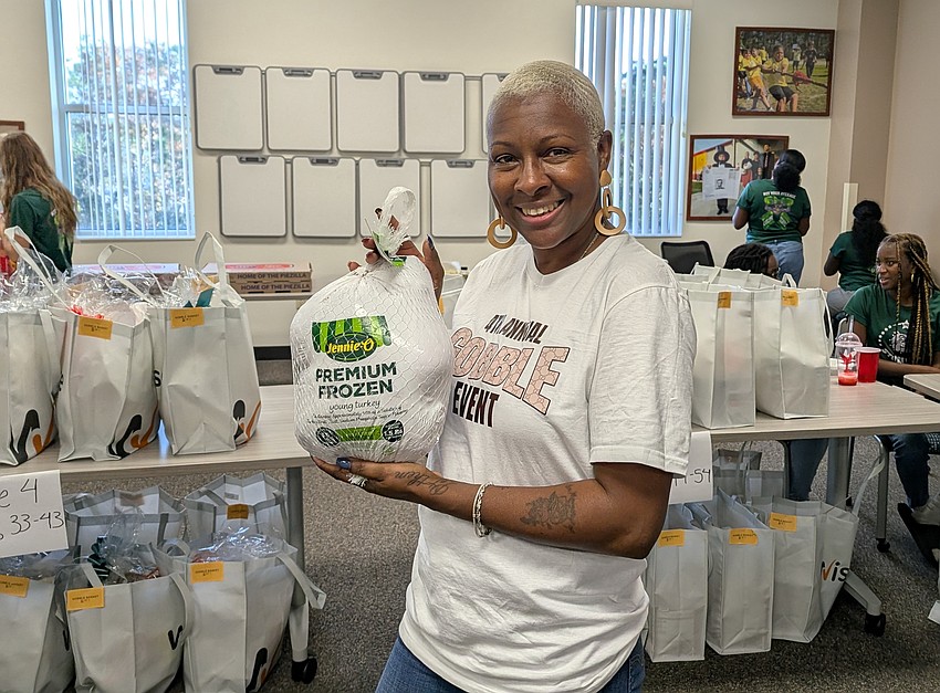 Lakisha Ayres-White, founder of the annual Gobble Event, holds up a turkey included in each of the Thanksgiving meals. Photo by Brent Woronoff