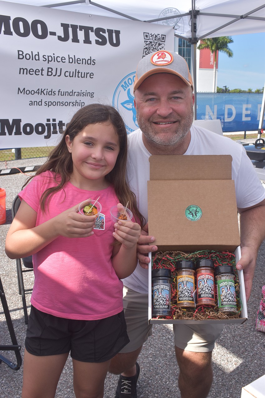 Olivia Whitman, 9 and her father Brandon Whitman of Moo-Jitsu, a spice company, hand out free samples of food with their spices.