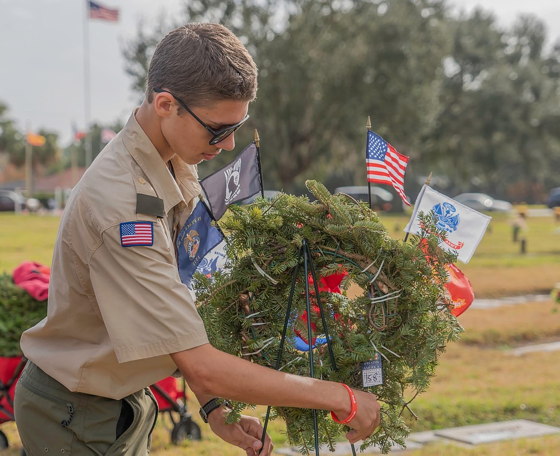 Ethan Tasior placed a wreath honoring each military branch during the National Wreaths Across America Day ceremony in 2024. Tasior has spent hours cataloging the veteran gravesites at Woodlawn Cemetery.
