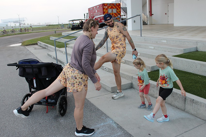 Laura, John, 3-year-old Lana-Ray, and 5-year-old Arie, find a place in front of the finish tower to stretch before the Florida Turkey Trot. The McCormick family was visiting from Summerville, South Carolina.