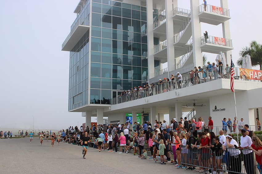 Spectators watch runners finish the 2025 Florida Turkey Trot in front of the Nathan Benderson Park finish tower.