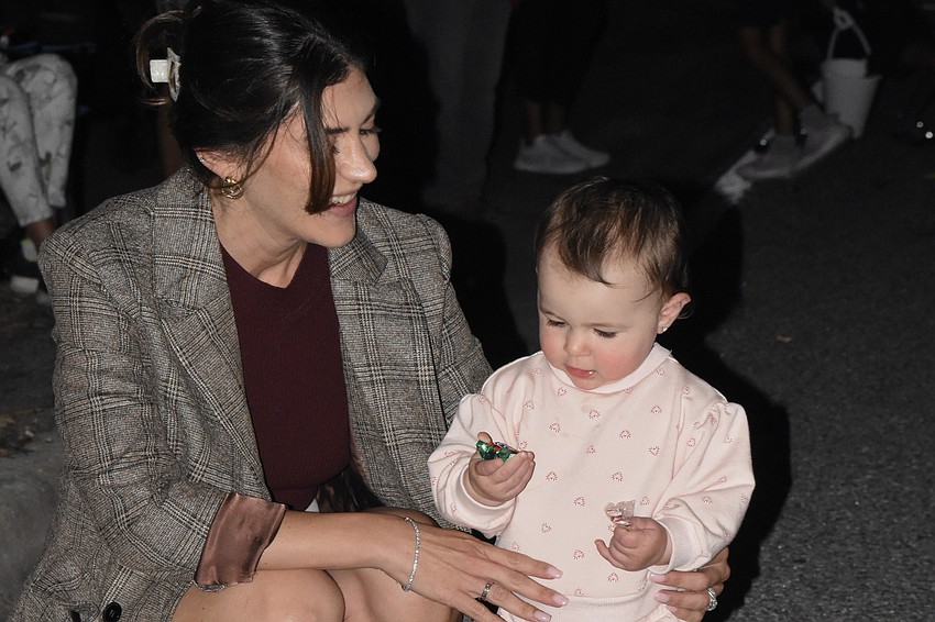 Courtney Bada watches as Cienna Bada, 1, picks up some of the candy left behind.
