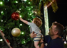 Sarasota's David Farr picks up 21-month-old Henry Farr, who is dazzled by the giant ornaments on the tree on The Green during the Mall at UTC's ongoing holiday celebration.