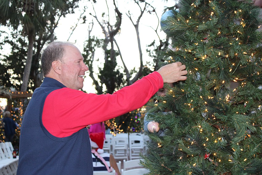Michael Bettner adds to the community Christmas tree by the gazebo at Christmas in the Garden.
