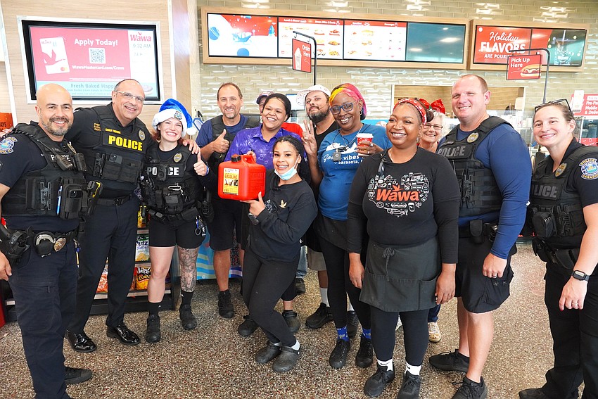 Chief Rex Troche, second from left, joins officers for a gasoline giveaway on Dec. 2 at Wawa on Fruitville Road, one of three locations the officers visited.