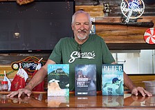 Shane Rawley poses for a photo on Dec. 2 at Shaner's Pizzeria with his three published books. From left: "A February Thaw: A Peter Cobb Adventure," "January Freeze: A Peter Cobb Adventure" and "Peter Cobb: Three Strikes You're Out."