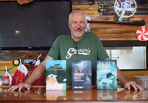 Shane Rawley poses for a photo on Dec. 2 at Shaner's Pizzeria with his three published books. From left: "A February Thaw: A Peter Cobb Adventure," "January Freeze: A Peter Cobb Adventure" and "Peter Cobb: Three Strikes You're Out."