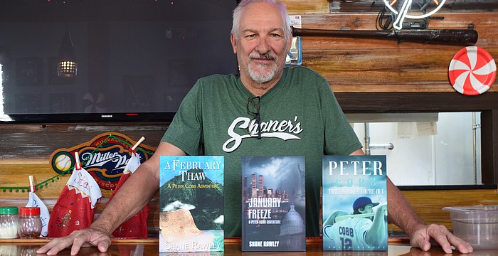 Shane Rawley poses for a photo on Dec. 2 at Shaner's Pizzeria with his three published books. From left: "A February Thaw: A Peter Cobb Adventure," "January Freeze: A Peter Cobb Adventure" and "Peter Cobb: Three Strikes You're Out."