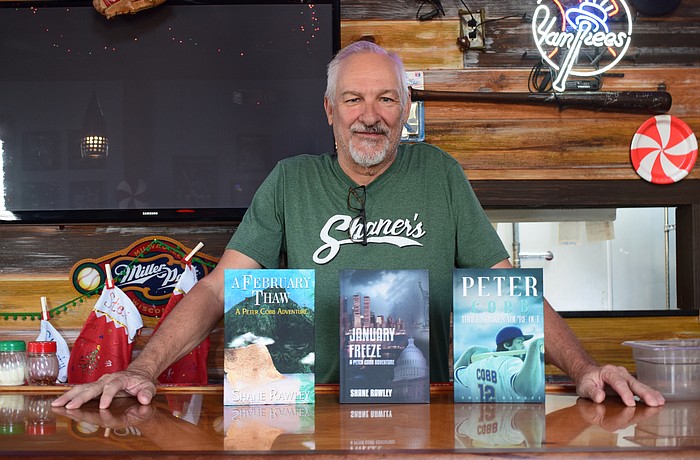 Shane Rawley poses for a photo on Dec. 2 at Shaner's Pizzeria with his three published books. From left: "A February Thaw: A Peter Cobb Adventure," "January Freeze: A Peter Cobb Adventure" and "Peter Cobb: Three Strikes You're Out."