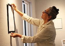 Artist JC Wayne hangs the ninth and final piece in her series "Atomic Universe," the latest installation at All Angels by the Sea Episcopal Church. The display will be up throughout the holiday season.