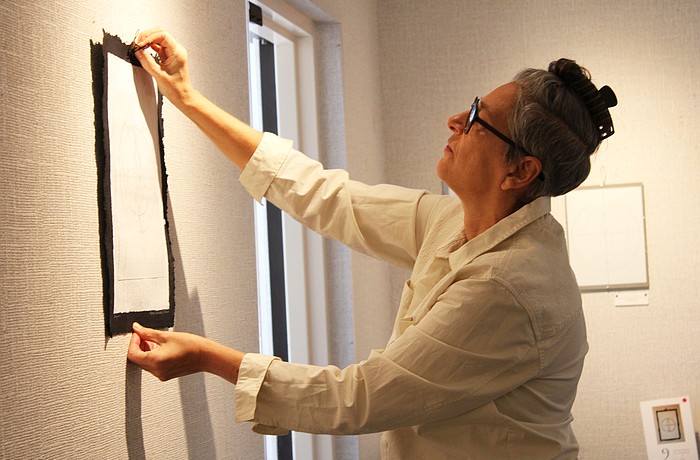 Artist JC Wayne hangs the ninth and final piece in her series "Atomic Universe," the latest installation at All Angels by the Sea Episcopal Church. The display will be up throughout the holiday season.