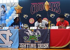Kymistrii Young (left), Elijah Golden (center) and Macaiden Brown (right) listen to coach Jared Clark's speech during Cardinal Mooney's early signing period ceremony.