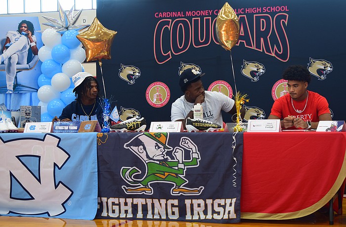 Kymistrii Young (left), Elijah Golden (center) and Macaiden Brown (right) listen to coach Jared Clark's speech during Cardinal Mooney's early signing period ceremony.
