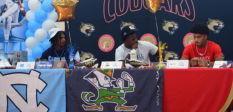Kymistrii Young (left), Elijah Golden (center) and Macaiden Brown (right) listen to coach Jared Clark's speech during Cardinal Mooney's early signing period ceremony.