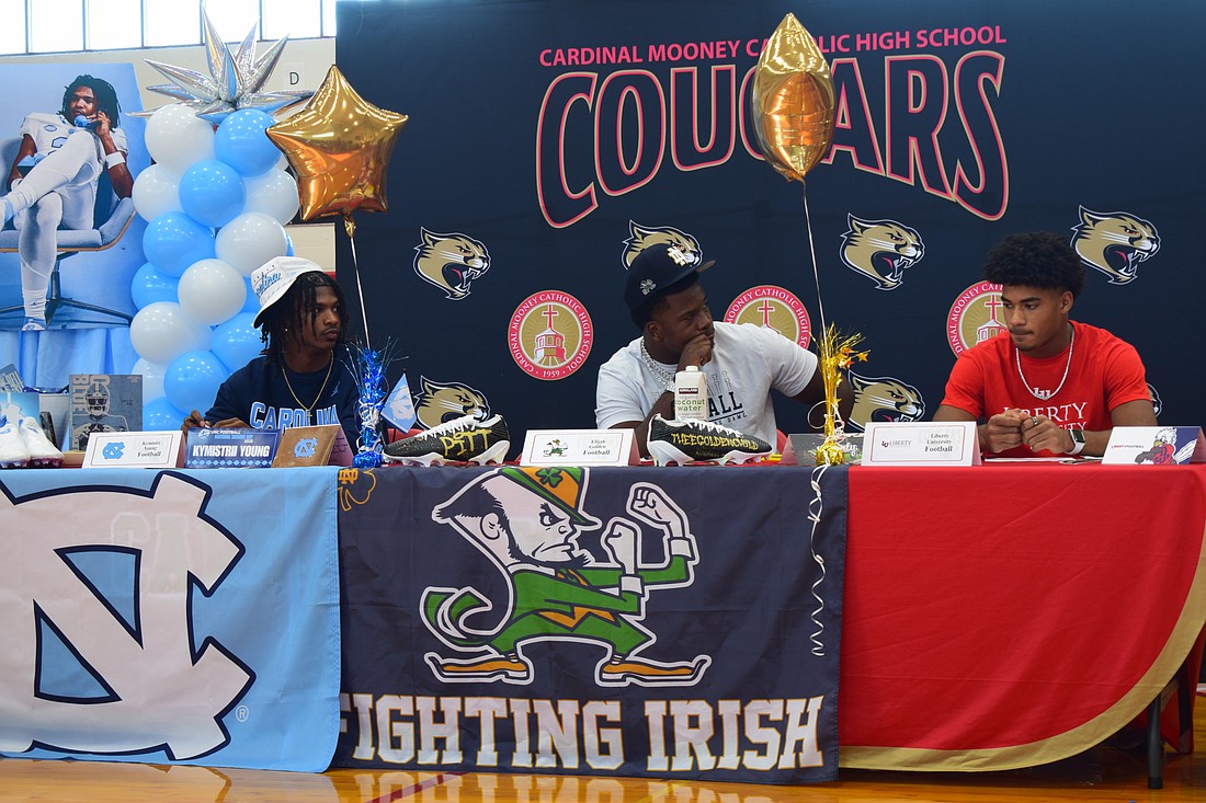 Kymistrii Young (left), Elijah Golden (center) and Macaiden Brown (right) listen to coach Jared Clark's speech during Cardinal Mooney's early signing period ceremony.