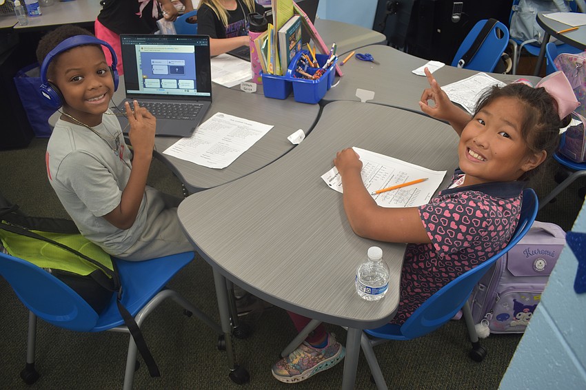 Fifth grader Travis Cambridge and third grader Joy Zhu sit together at a table.