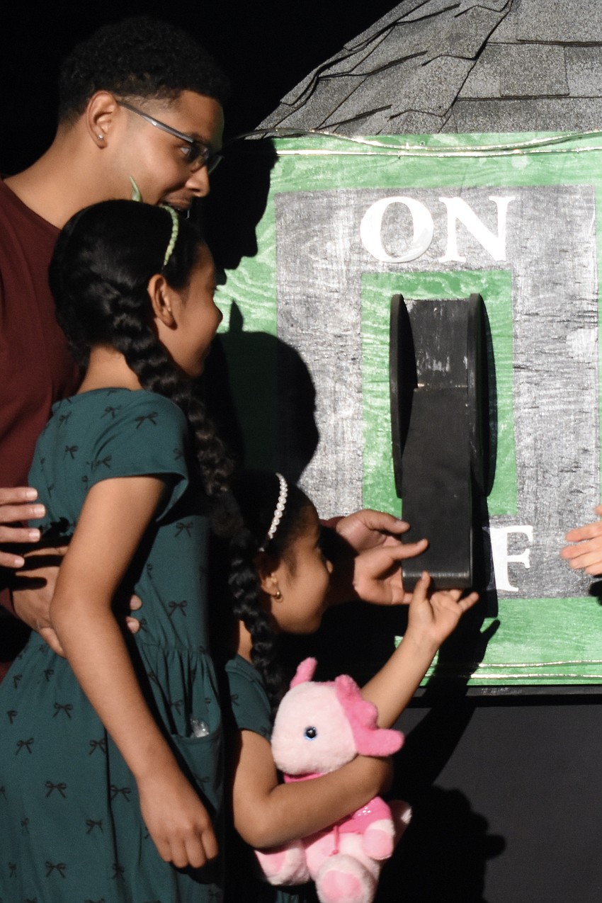 Marcus Pinckney, Nadia Pinckney, 9, and Alani Pinckney, 5, flip the switch.