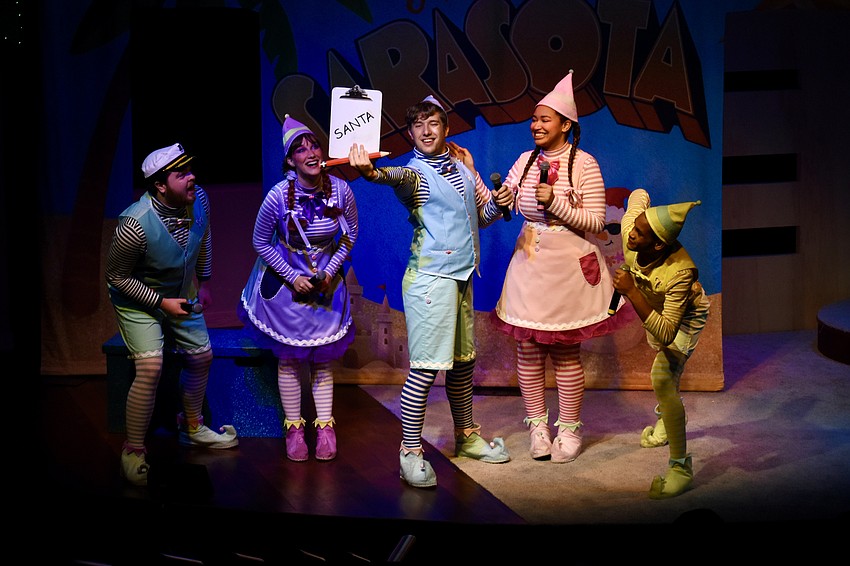 Jolly (Flynn Nolen), Candy (Christiana Allison), Jangle (Ray Barber), Tinsel (Vanessa Smith), and Jingle (Mareece Love) are gathered as Jingle tries to spell Santa Claus' name.