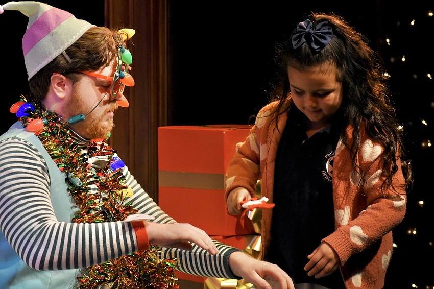 Jolly (Flynn Nolen) gets a festive look from Amy Sevilla, a kindergartener at Phillippi Shores Elementary School who has been invited on stage for the 