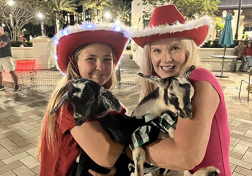 Myakka City 12-year-old Aliyah Burnett helps her neighbor, Corinn Smith of Blissful Goat Yoga, with the goats. She dressed them in Christmas outfits for Ranch Nite Wednesday Dec. 3.