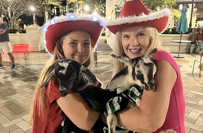 Myakka City 12-year-old Aliyah Burnett helps her neighbor, Corinn Smith of Blissful Goat Yoga, with the goats. She dressed them in Christmas outfits for Ranch Nite Wednesday Dec. 3.