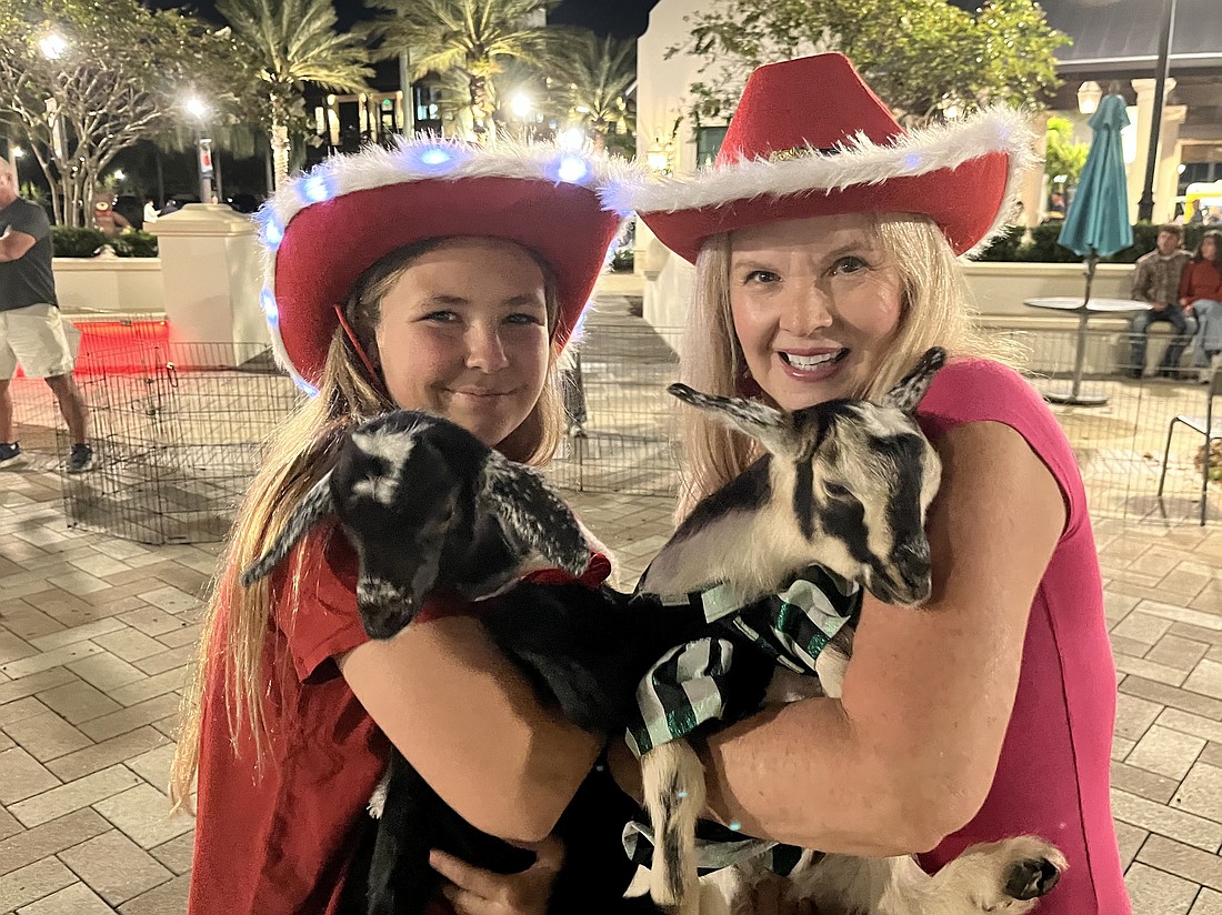 Myakka City 12-year-old Aliyah Burnett helps her neighbor, Corinn Smith of Blissful Goat Yoga, with the goats. She dressed them in Christmas outfits for Ranch Nite Wednesday Dec. 3.