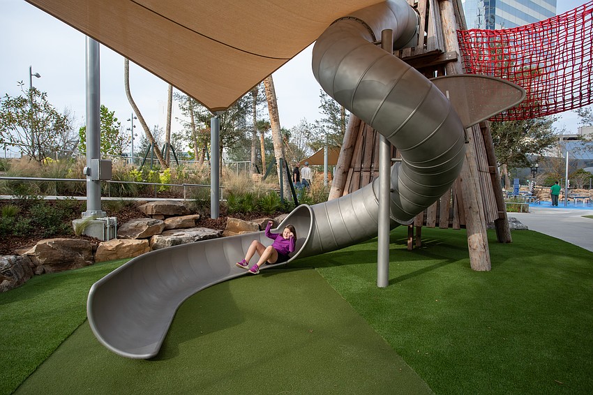 Riverfront Plaza park includes a shaded area with activities for kids, including a slide.