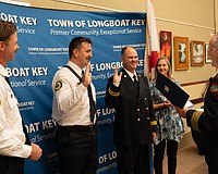 Firefighter paramedic Aaron Maness and Training Captain David Eggleston raise their hands to recite an oath before receiving their badges. The two had already completed their training but had not officially received their badges in a ceremony. Maness was later awarded the Medal of Honor by Fire Chief Paul Dezzi.