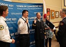 Firefighter paramedic Aaron Maness and Training Captain David Eggleston raise their hands to recite an oath before receiving their badges. The two had already completed their training but had not officially received their badges in a ceremony. Maness was later awarded the Medal of Honor by Fire Chief Paul Dezzi.
