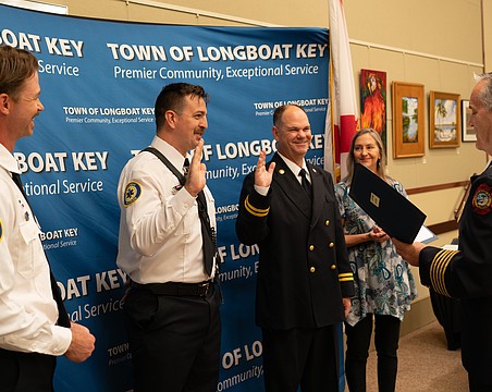 Firefighter paramedic Aaron Maness and Training Captain David Eggleston raise their hands to recite an oath before receiving their badges. The two had already completed their training but had not officially received their badges in a ceremony. Maness was later awarded the Medal of Honor by Fire Chief Paul Dezzi.