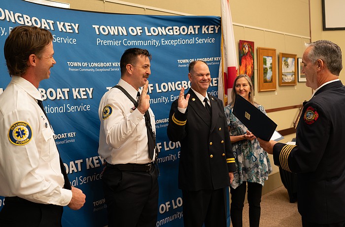 Firefighter paramedic Aaron Maness and Training Captain David Eggleston raise their hands to recite an oath before receiving their badges. The two had already completed their training but had not officially received their badges in a ceremony. Maness was later awarded the Medal of Honor by Fire Chief Paul Dezzi.